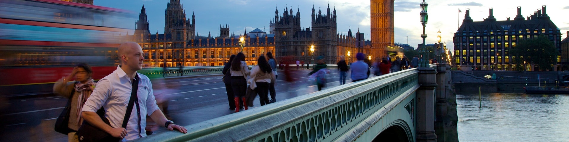 Uma ponte com uma torre de relógio e um edifício histórico ao fundo.