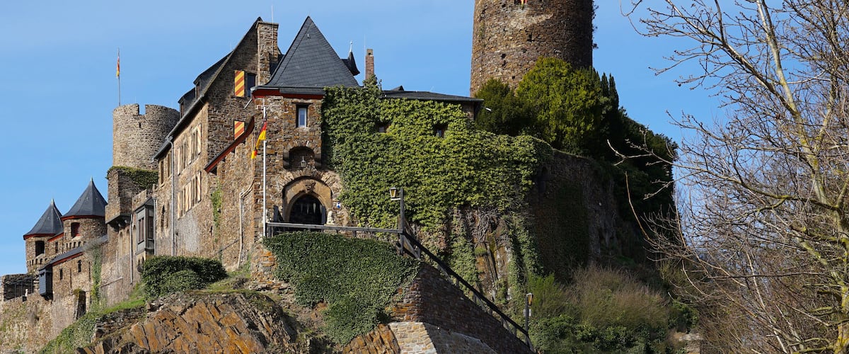A historic castle with stone walls, multiple towers, and ivy-covered structures.