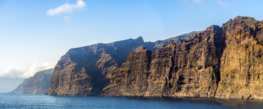 A rugged coastline with steep cliffs and a calm sea.