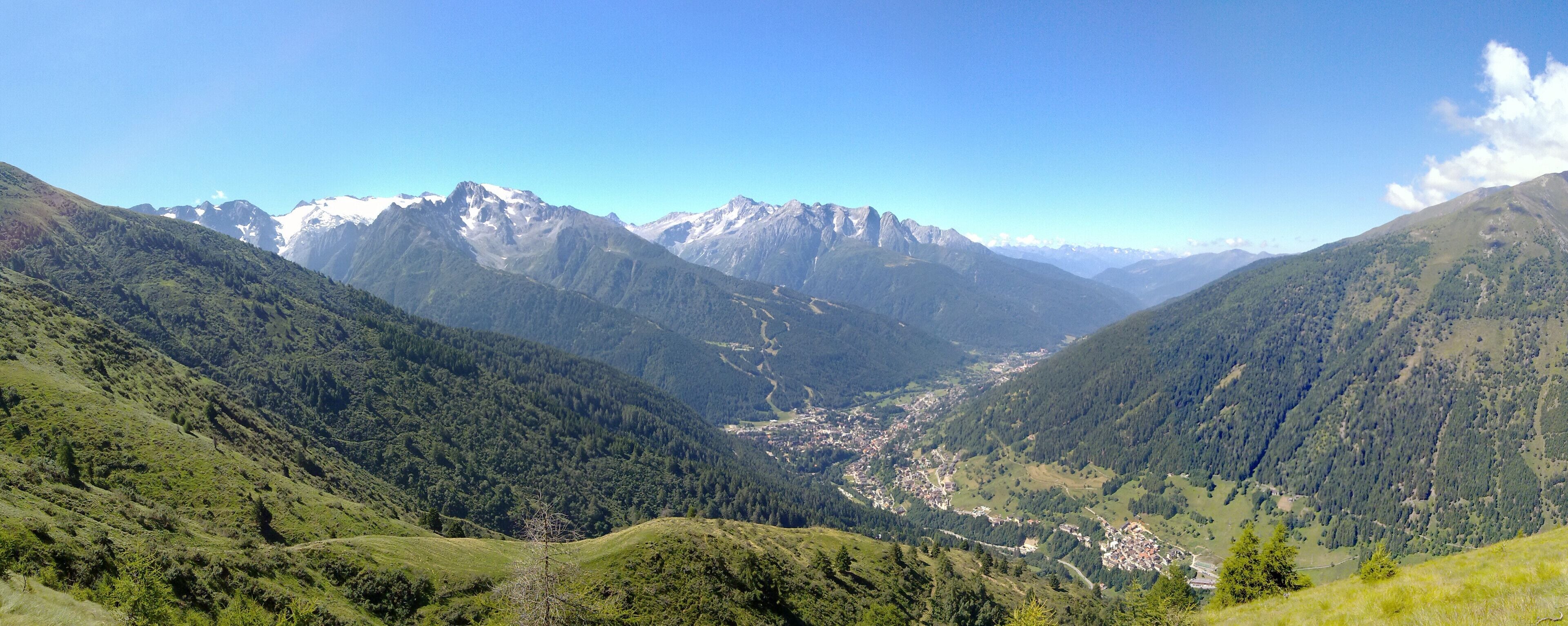 A valley with a town surrounded by mountains and dense forests.