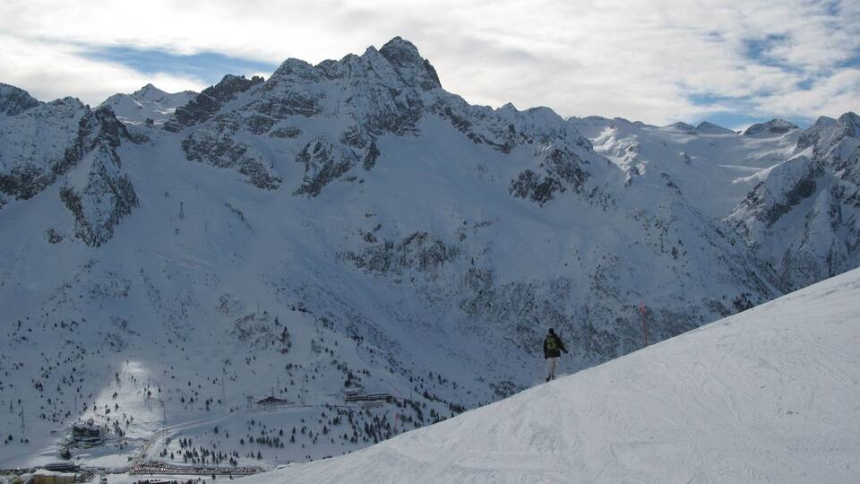 A snow-covered mountain range with a ski slope and a ski lift.