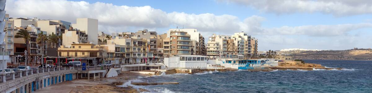 A coastal town with buildings, a pier, and rocky shoreline.
