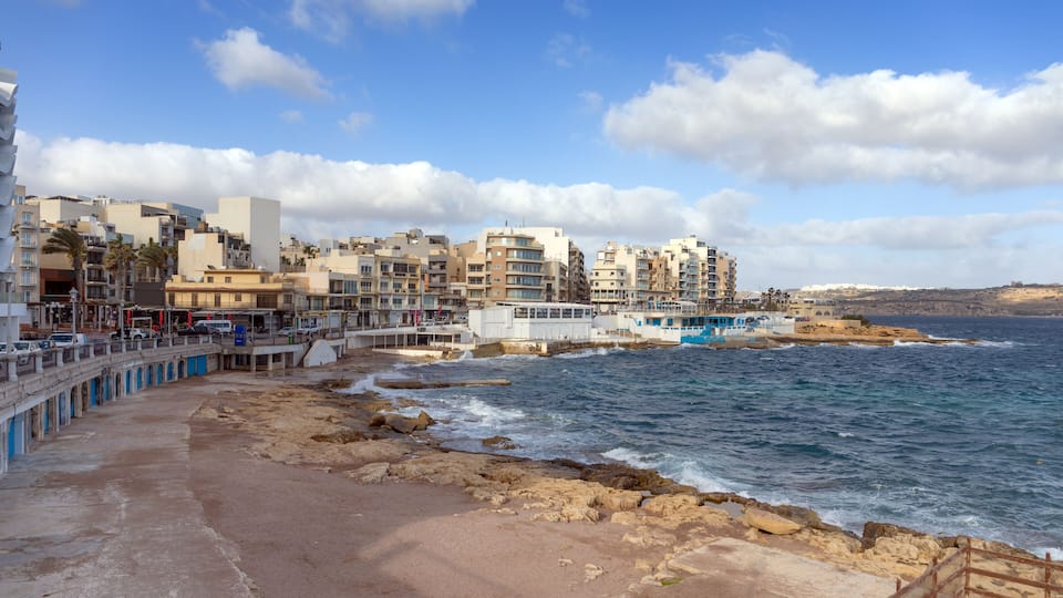 A coastal town with buildings, a pier, and rocky shoreline.