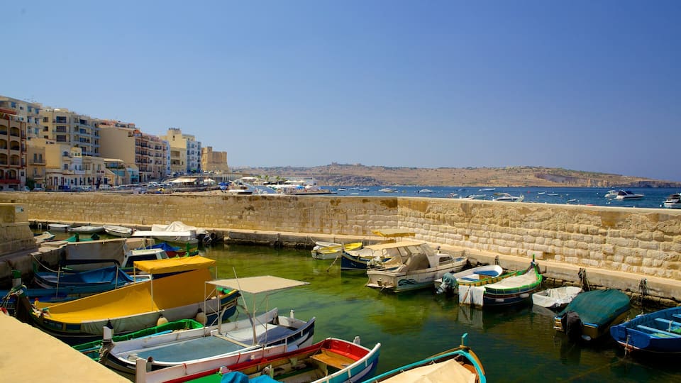 A harbor with various boats docked, a stone wall, and buildings in the background.