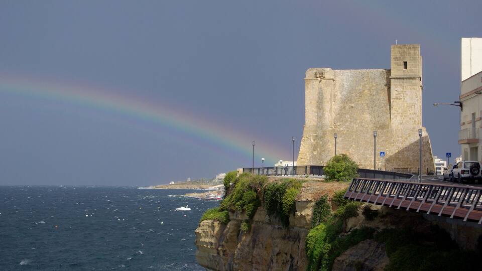 A coastal castle with a rainbow over the sea.