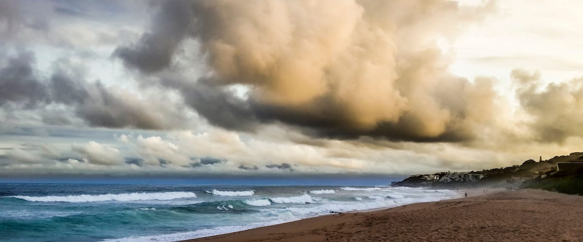 A beach with waves crashing onto the shore under a dramatic sky.