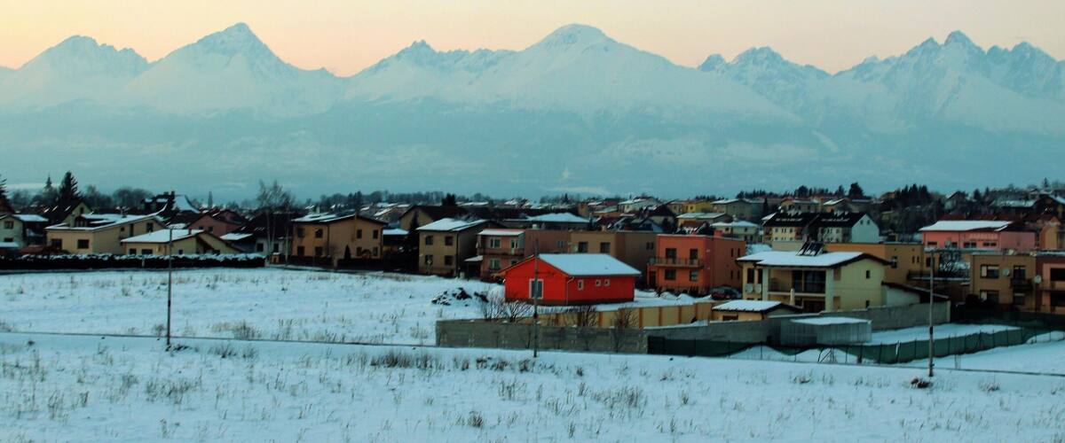 A snowy landscape with a town and mountains in the background.