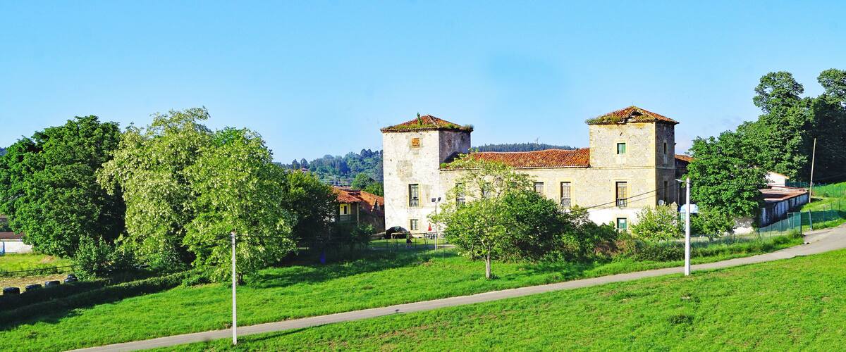 A historic building with two towers, surrounded by lush green fields and trees.