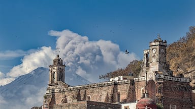 Una iglesia histórica con un campanario y una montaña al fondo.