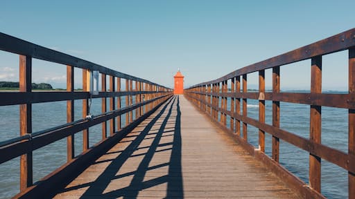 Distant view of lighthouse on pier against clear sky