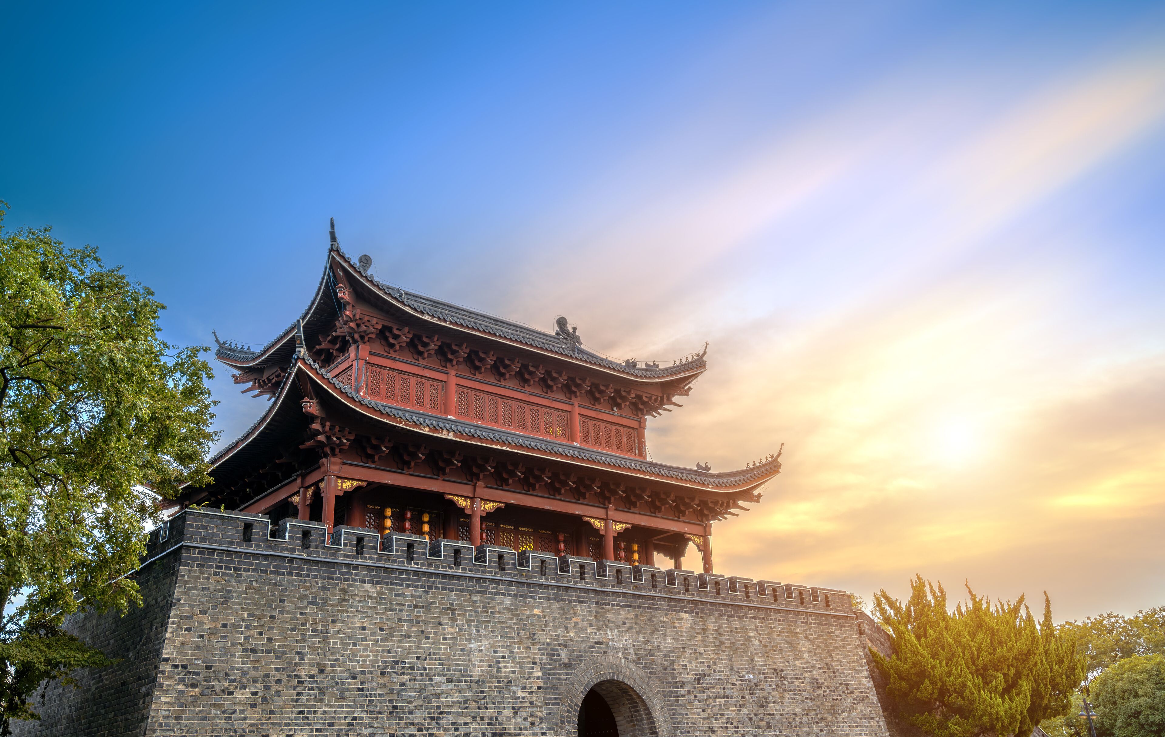 A traditional Chinese building with ornate architecture, a stone wall, and a clear sky.