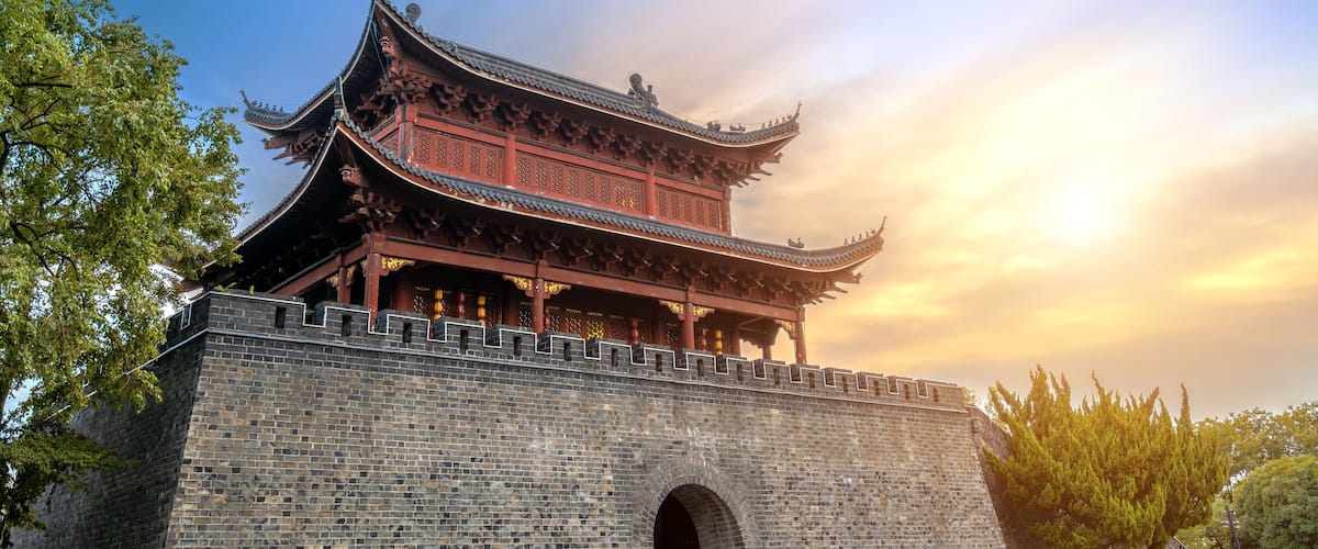A traditional Chinese building with ornate architecture, a stone wall, and a clear sky.