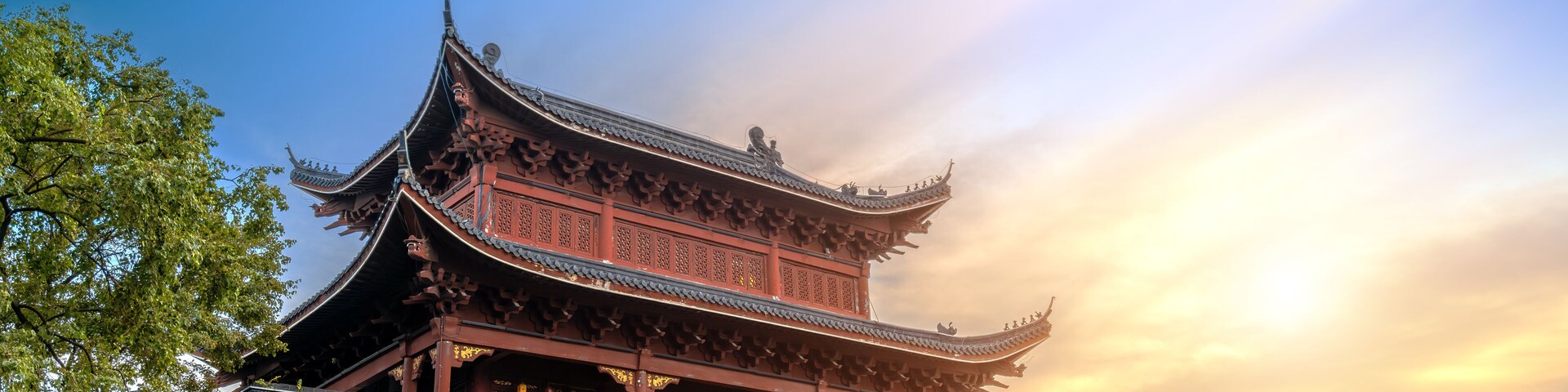 A traditional Chinese building with ornate architecture, a stone wall, and a clear sky.