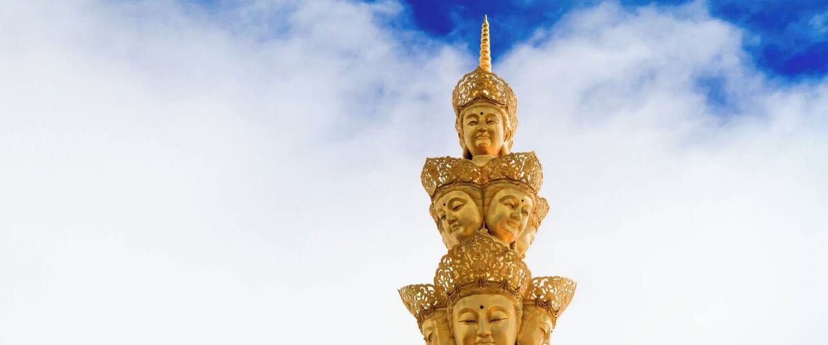 A multi-tiered golden statue with intricate designs and a lotus flower.