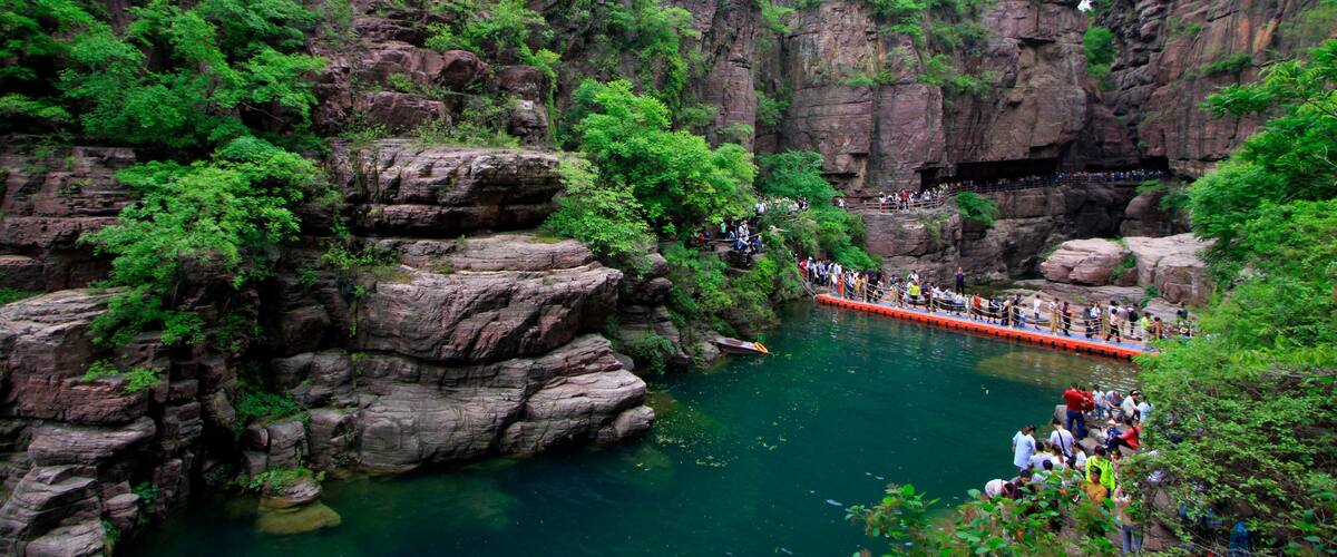 A river with a bridge, surrounded by rocky cliffs and greenery.