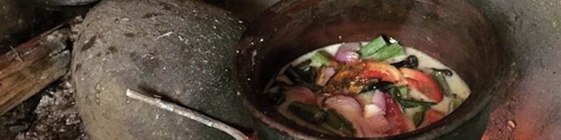 Montagem de cozinha tradicional com um caldeirão sobre fogo aberto, contendo um ensopado com legumes.