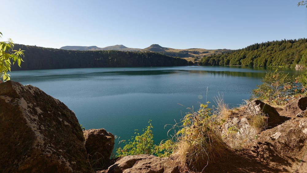 A calm lake surrounded by hills and dense forests.