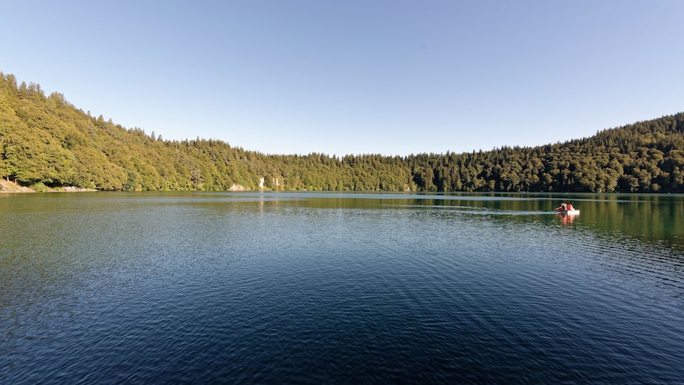 A calm lake surrounded by dense forest and hills.