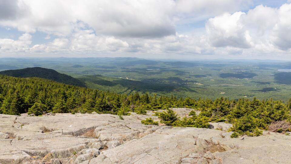 A mountainous landscape with dense forests and rocky terrain.
