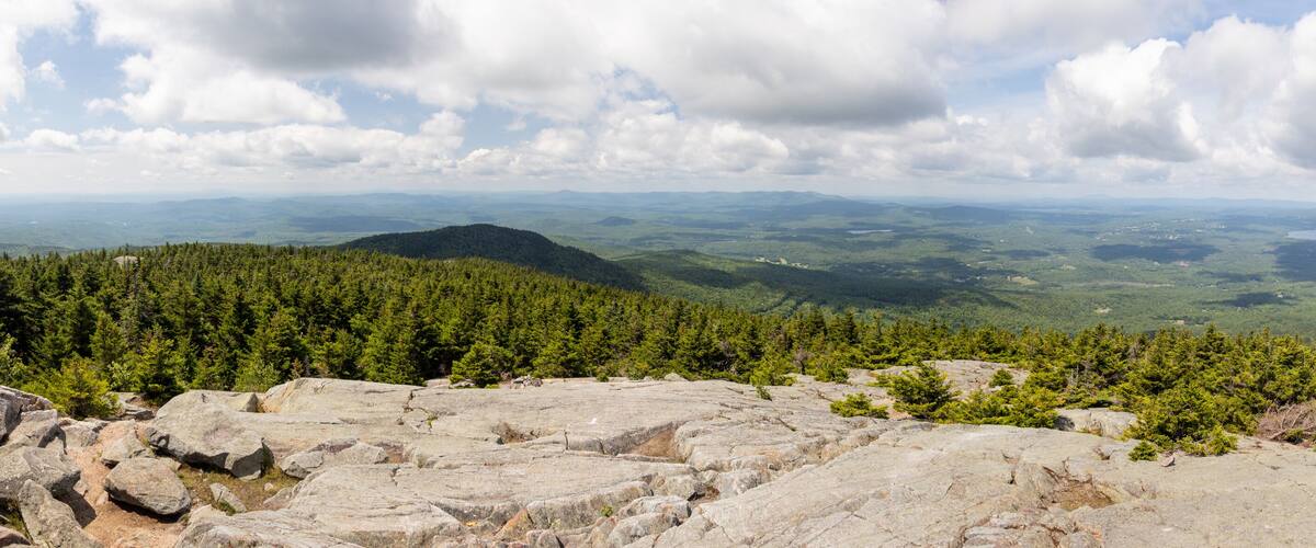 A mountainous landscape with dense forests and rocky terrain.