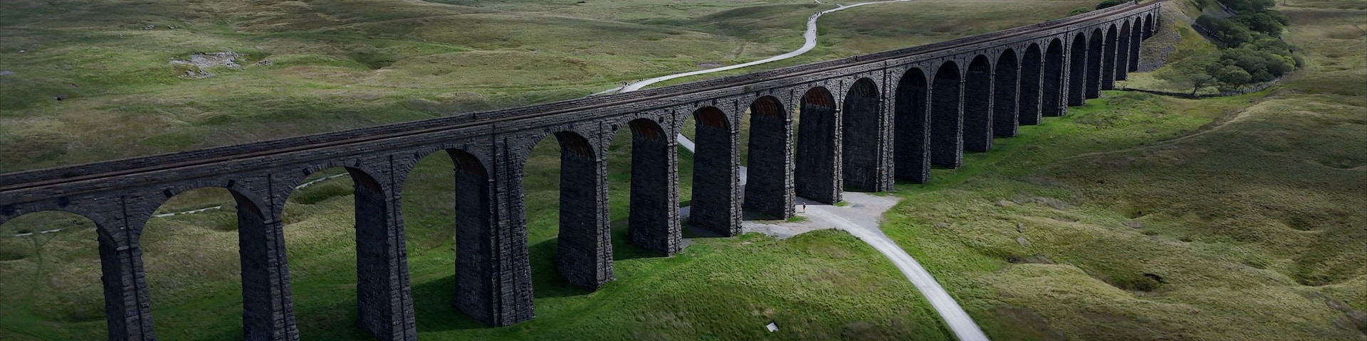 En lang viadukt strækker sig over en dal, med en snoet vej langs siden.