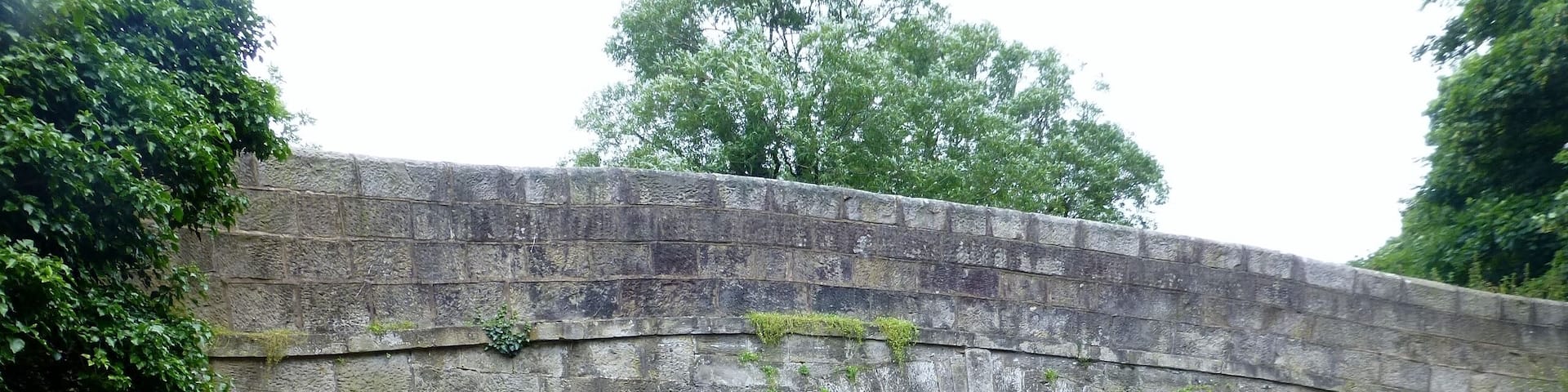 A stone bridge over a river with a paved path leading to it.