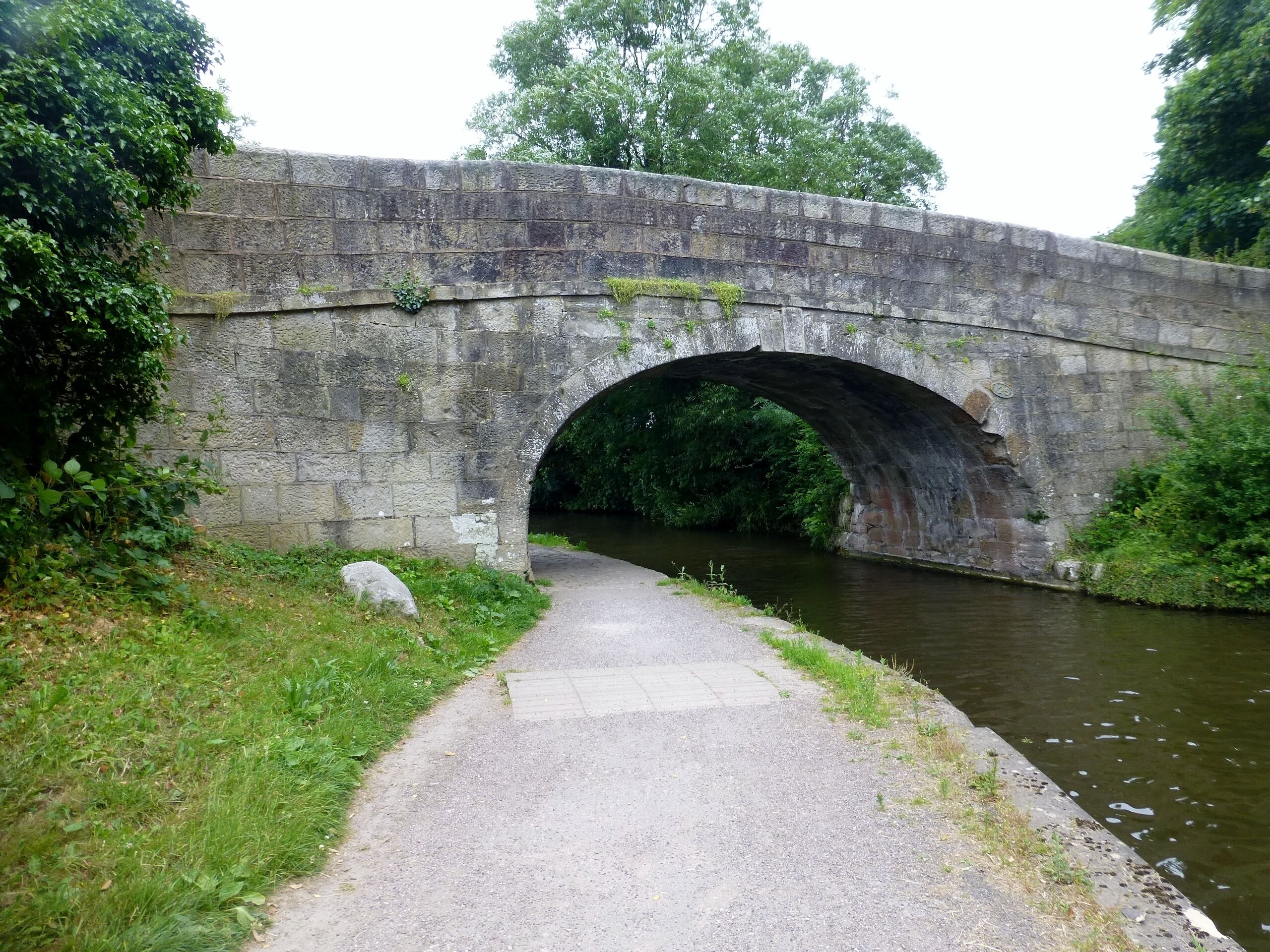 A stone bridge over a river with a paved path leading to it.