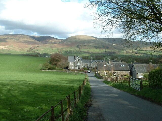 A rural landscape with a house, a road, and rolling hills.