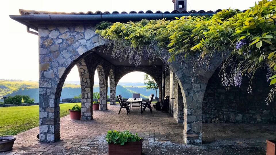A stone pergola with a view of the countryside.