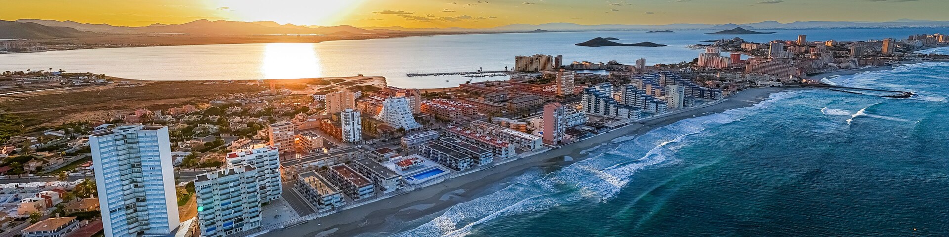 A coastal cityscape with a prominent beachfront, high-rise buildings, and a sunset over the ocean.