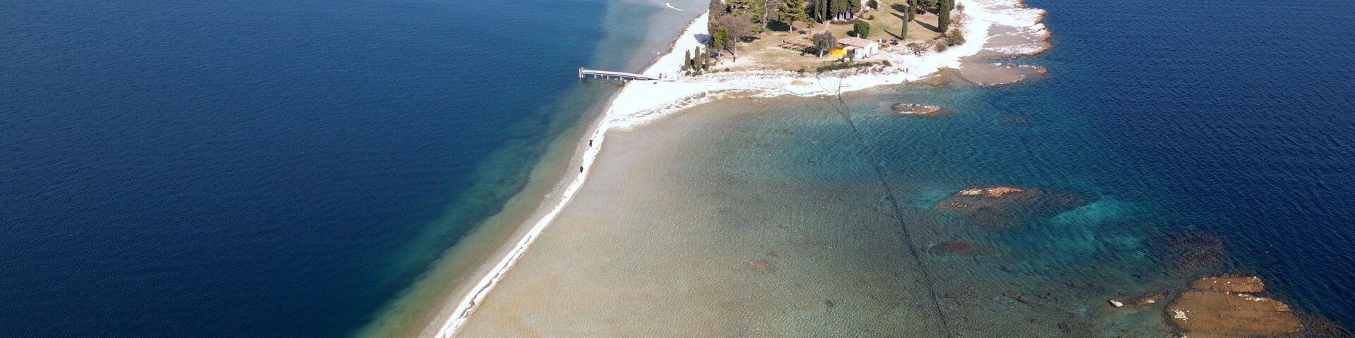 Italy, Lake Garda ,San Biagio Island , Rabbit Island - the shallow waters of the lake allow you to walk and reach the island on foot - water emergency in Lombardy , drought lowering of the water level