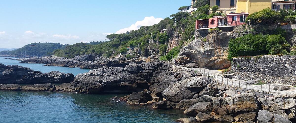 A coastal town with rocky cliffs, a stone pathway, and colorful buildings.