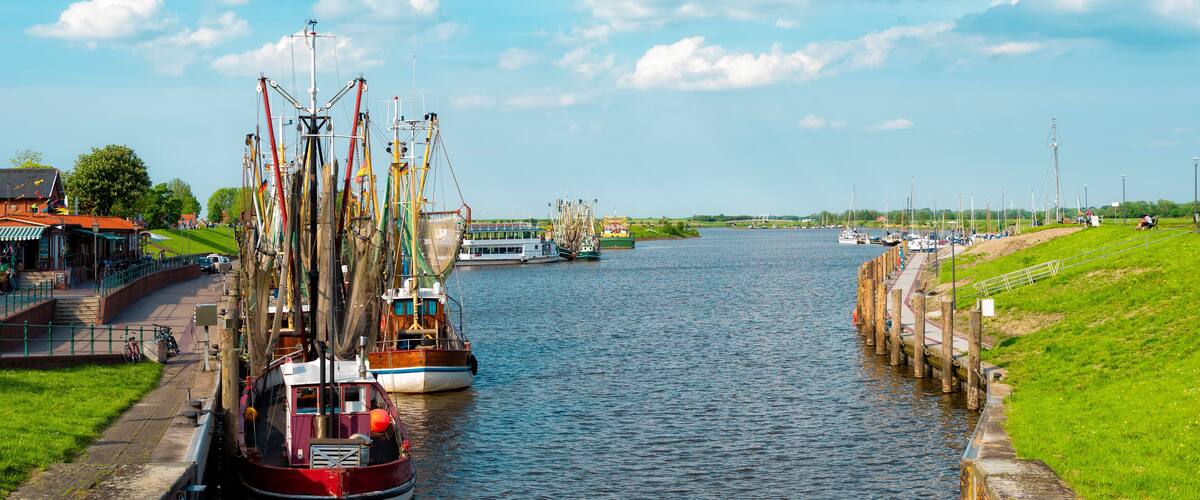A canal with boats, a bridge, and a grassy bank.