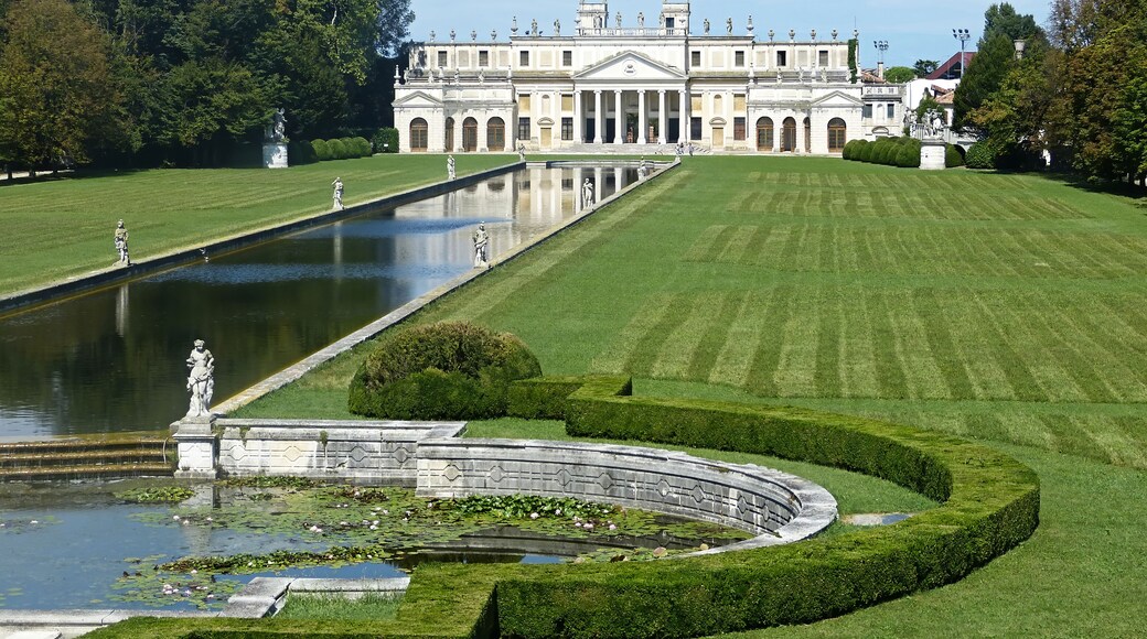A grand classical building with a symmetrical garden, a reflecting pool, and statues.