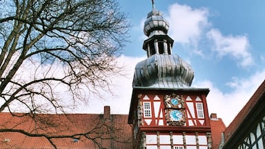 A traditional half-timbered building with a clock tower and a cobblestone courtyard.