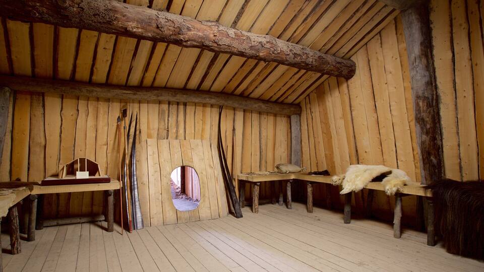 A rustic wooden interior with a sloped ceiling, wooden beams, and a circular window.