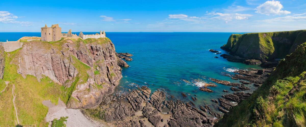 Panorama of a cliff with ancient castle in a bay with blue sky and white clouds in Dunnottar Castle, near Stonehaven, Aberdeenshire