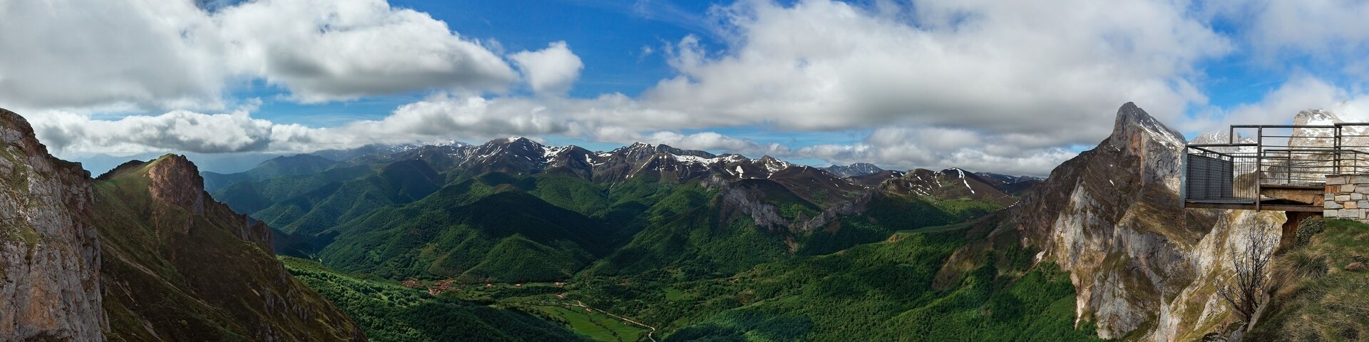 Paisaje montañoso con un valle, una carretera sinuosa y una plataforma de observación.