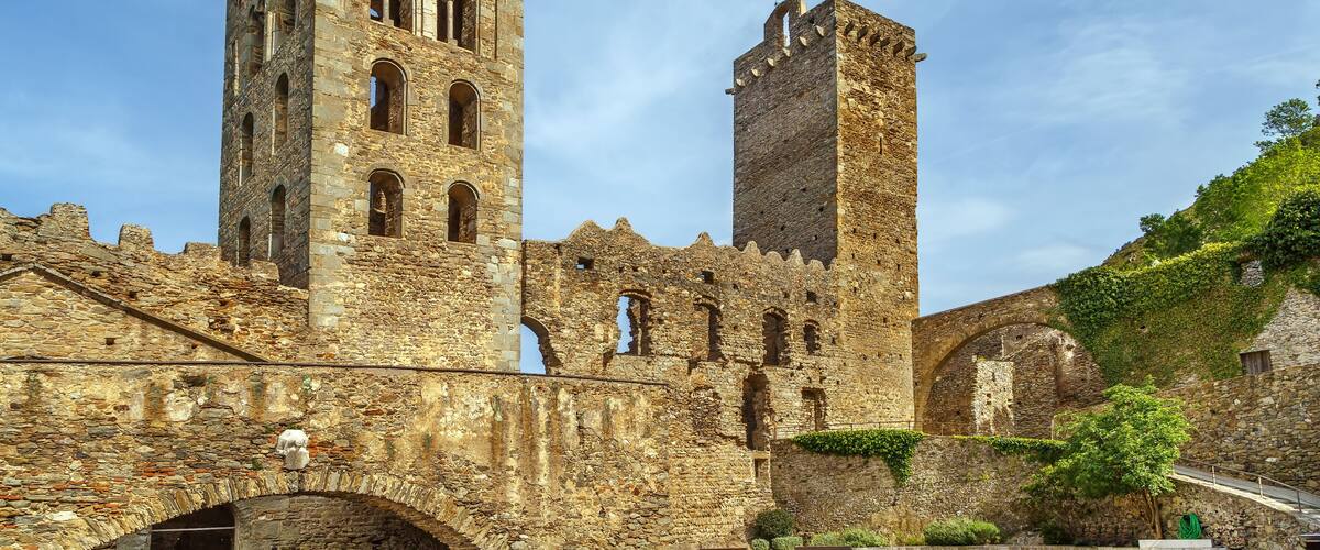 A historic stone tower with arched windows and a tall, narrow tower beside it.