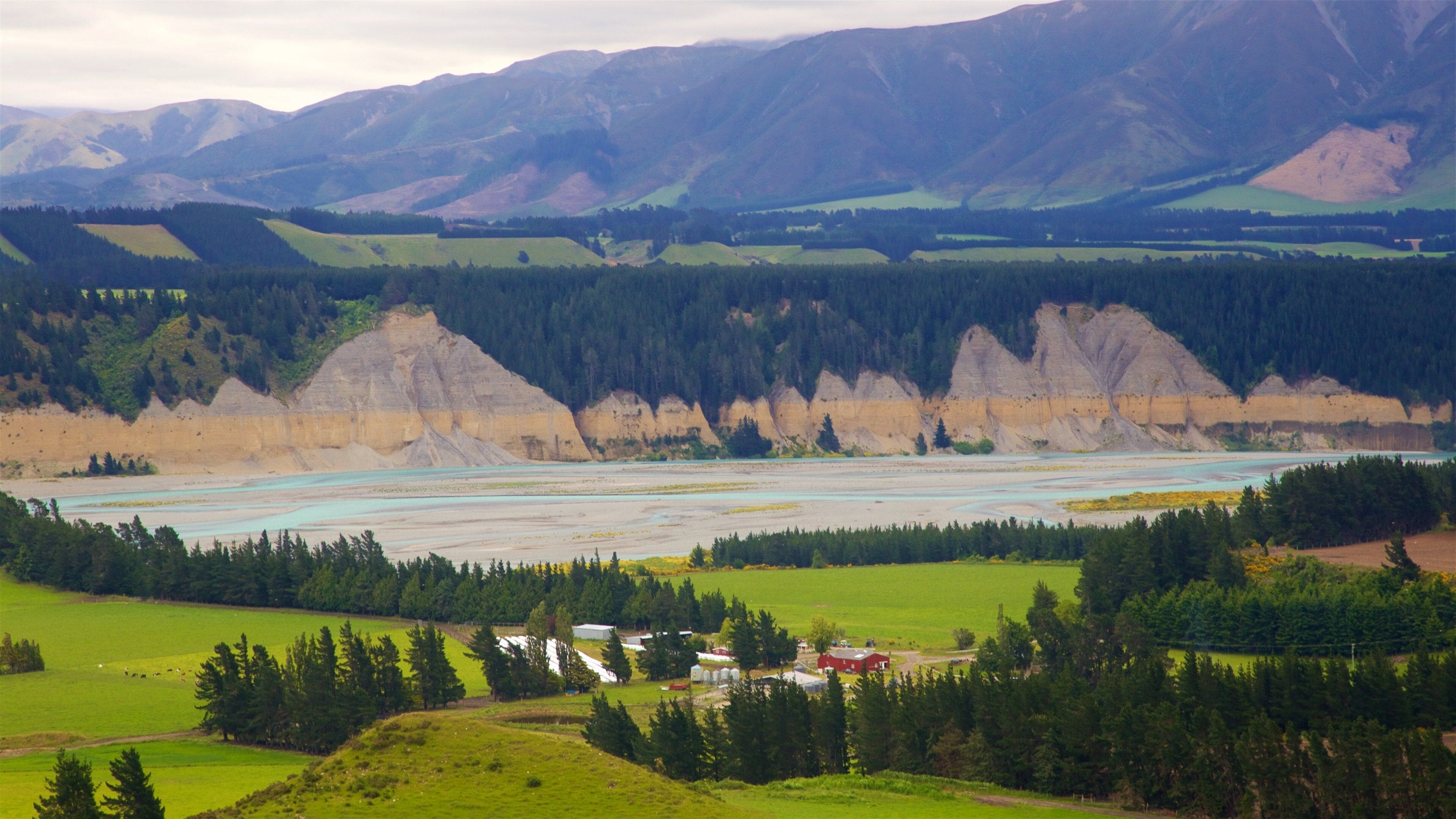 A river valley with a forested area and a small settlement.
