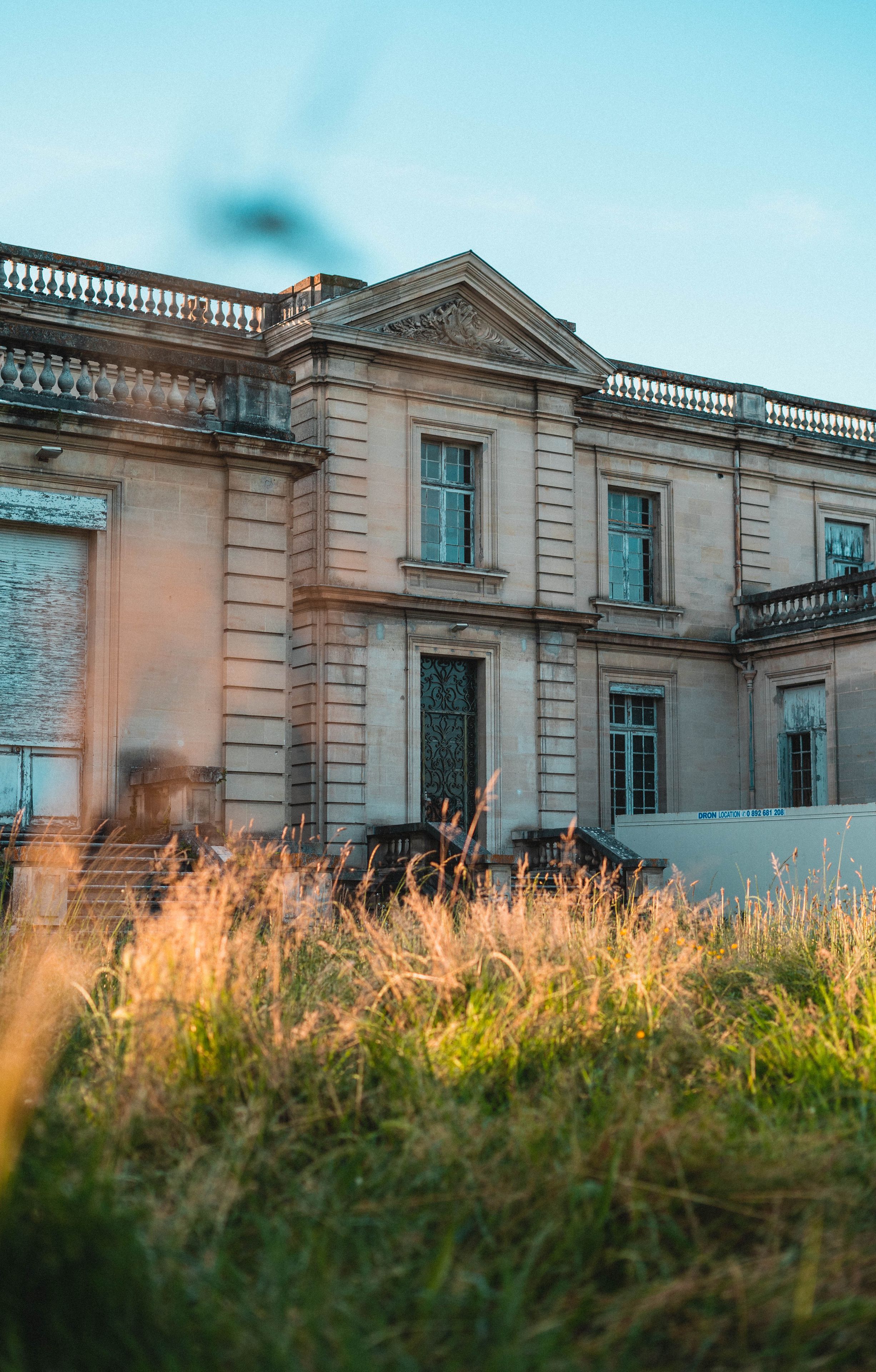 A historic building with classical architecture, featuring a symmetrical facade, multiple windows, and a decorative balustrade.