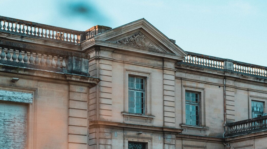 A historic building with classical architecture, featuring a symmetrical facade, multiple windows, and a decorative balustrade.
