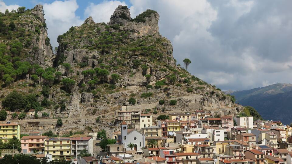 A coastal town with colorful buildings, a prominent church, and rocky cliffs.