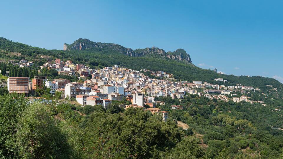 A town nestled on a hillside with buildings and rocky cliffs.