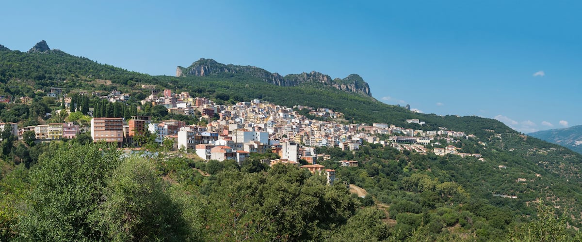 A town nestled on a hillside with buildings and rocky cliffs.