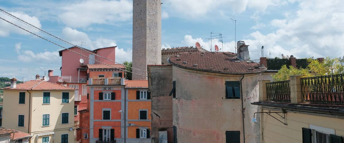 A historic tower, colorful buildings, and a canal.