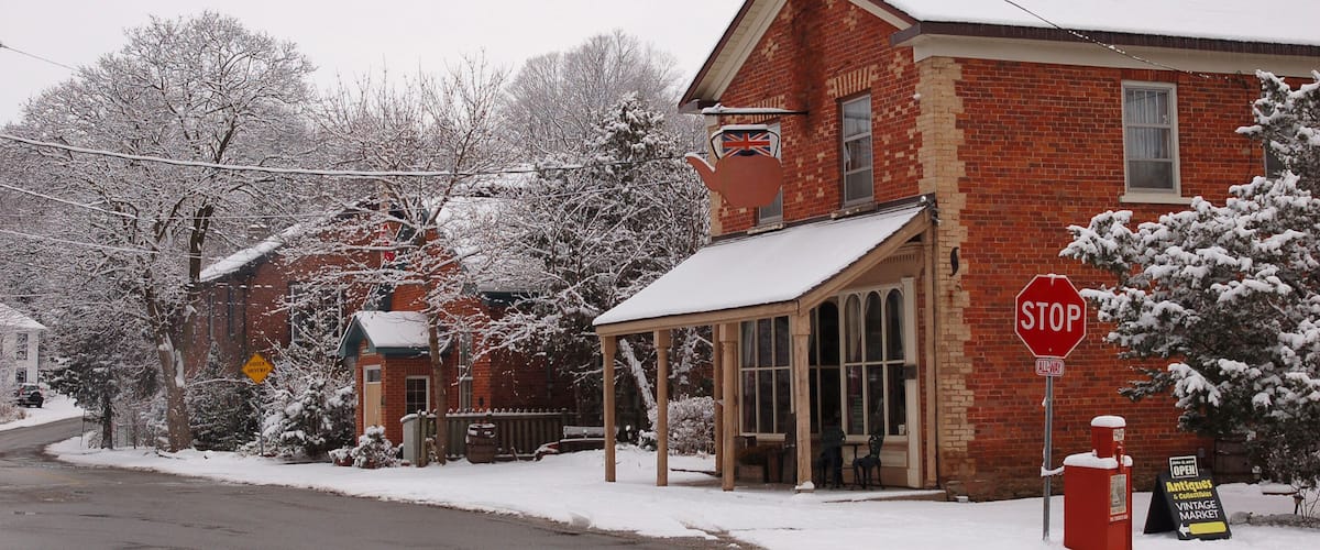 A snow-covered building with a stop sign and a sign for an antiques market.