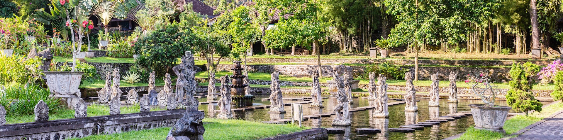 A serene garden with stone statues, a pond, and lush greenery.