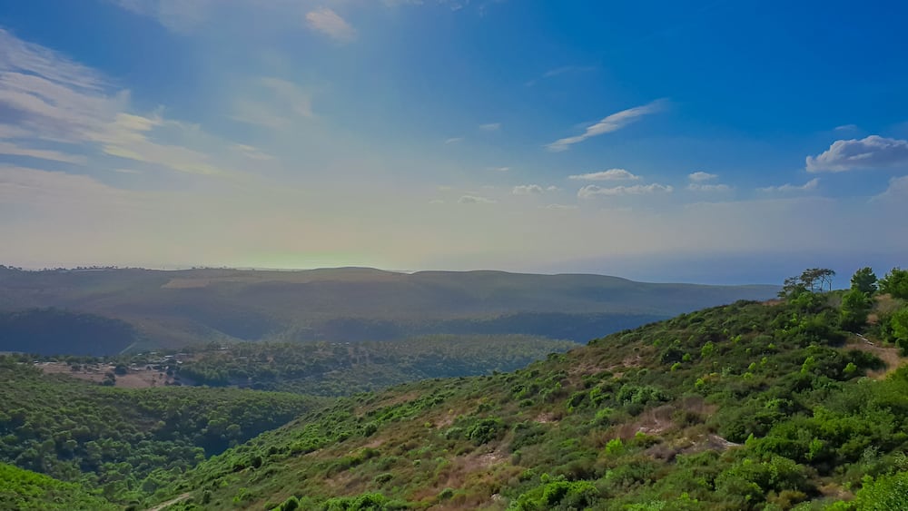 Un paysage montagneux caractérisé par une végétation luxuriante et un ciel d’un bleu éclatant.
