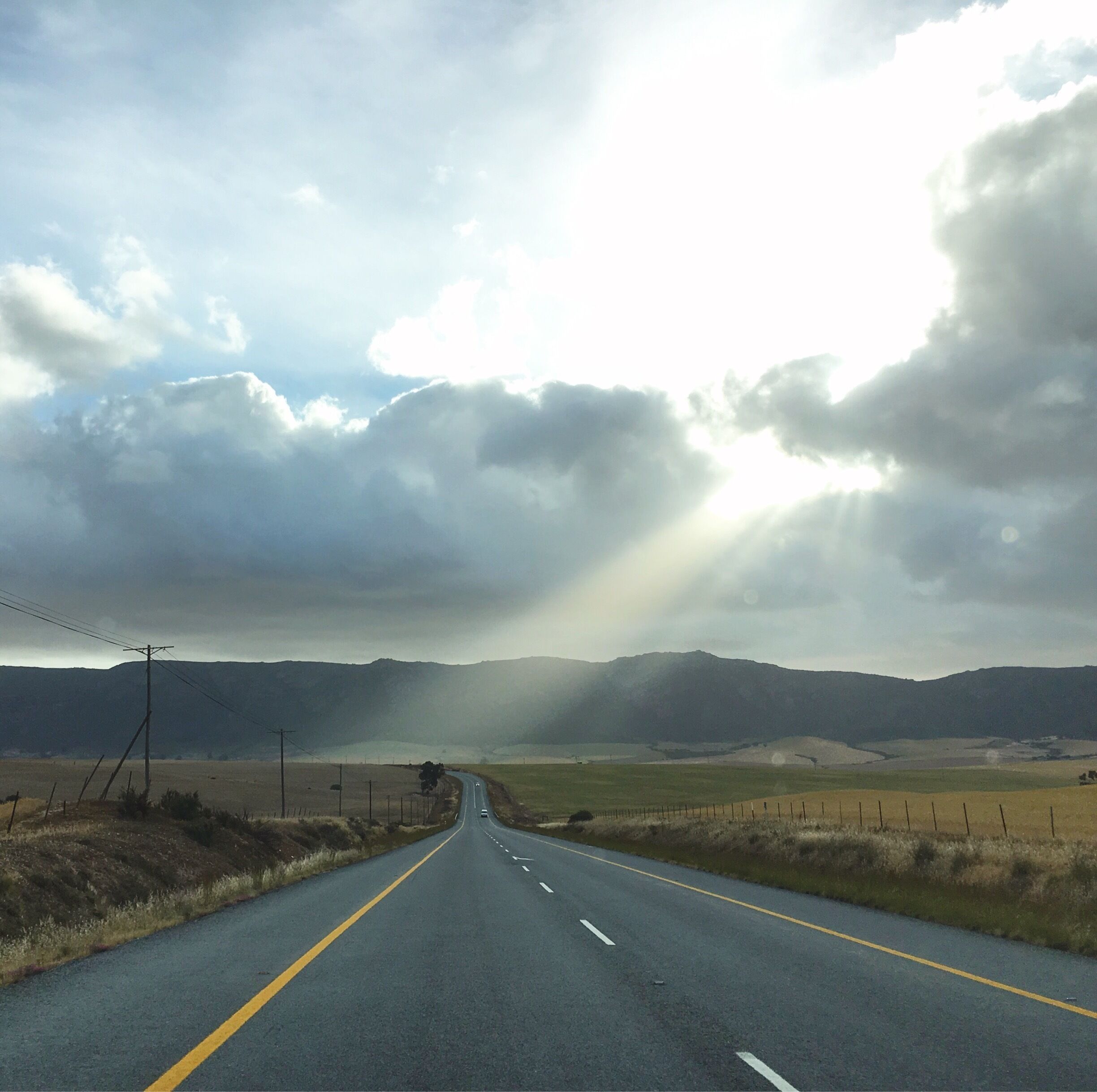 A rural road with a clear sky and distant mountains.